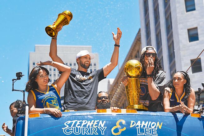 NBA冠军勇士在旧金山庆功游行，当家射手柯瑞在巴士上高举他的总冠军赛MVP奖盃。（路透）